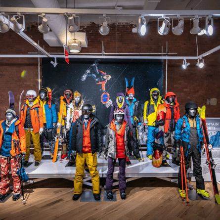 Ski and snowboard display featuring winter-clad mannequins with skis and snowboards in an indoor showroom