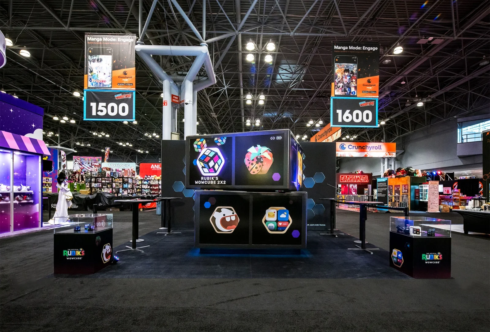 Rubik’s WowCube 2x2 display booth at a convention, with product screens, branded counters, and overhead booth signs numbered 1500 and 1600.