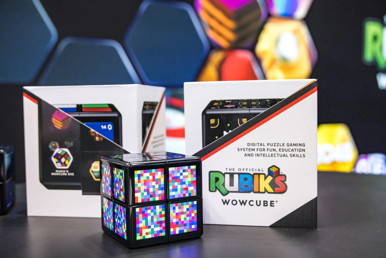 Rubik’s WowCube with colorful pixel-patterned faces displayed in front of its product packaging