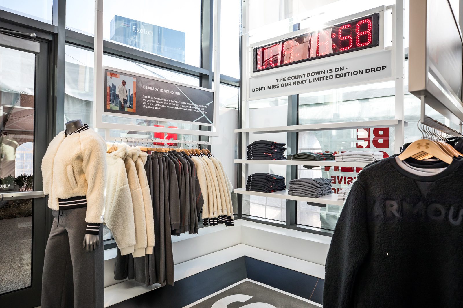 Under Armour store interior displaying fleece jackets, folded clothing, and a countdown sign for a limited-edition drop.
