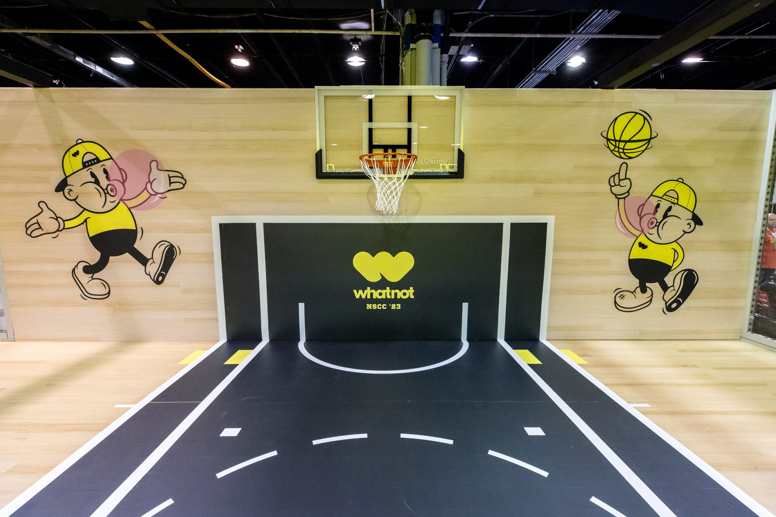 Whatnot NSCC '23 basketball court display with hoop, cartoon basketball mascots, and Whatnot branding.