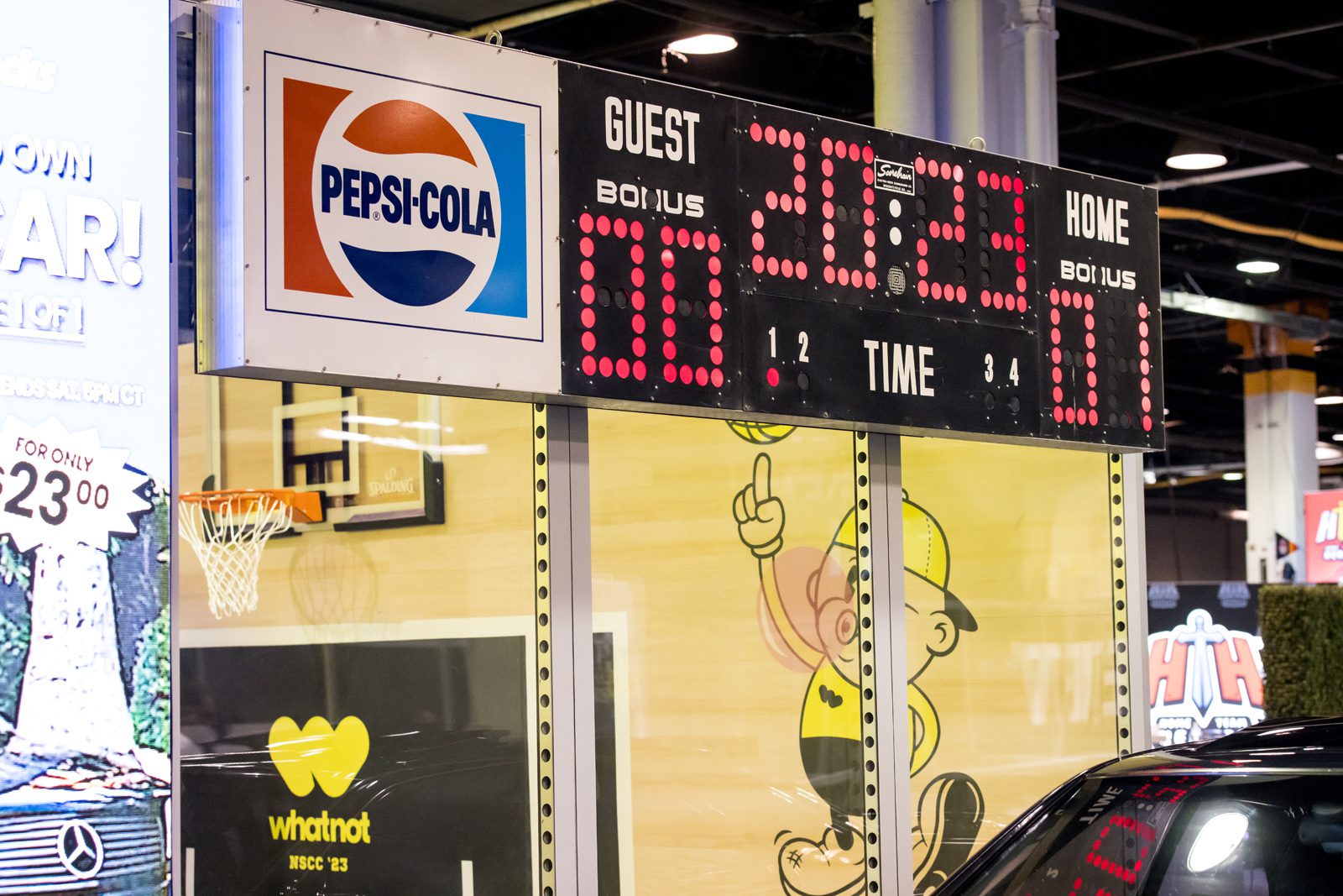Pepsi-Cola basketball scoreboard above a Whatnot NSCC ’23 display