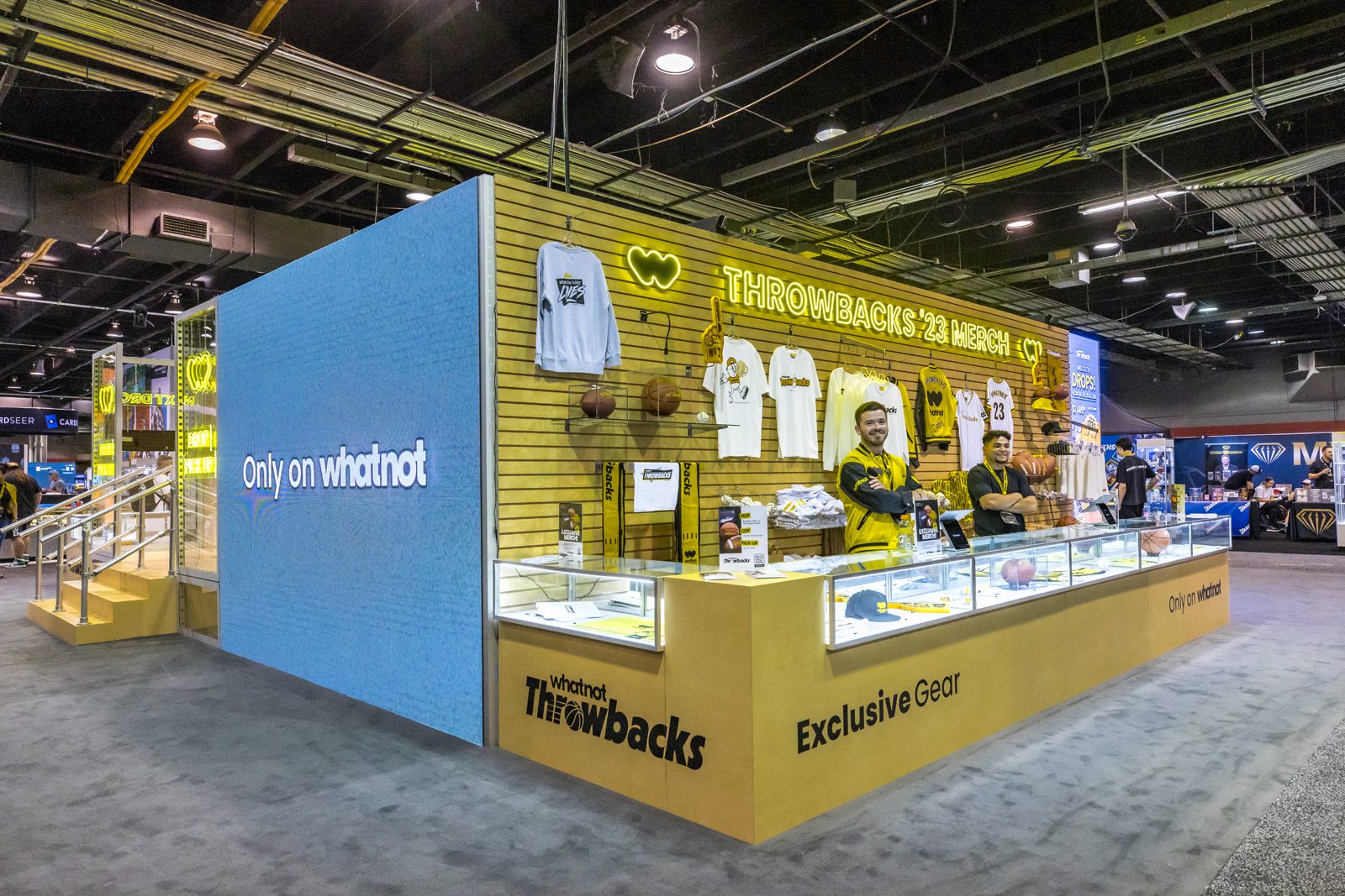 Whatnot Throwbacks ’23 merchandise booth displaying apparel and sports memorabilia in a convention hall.