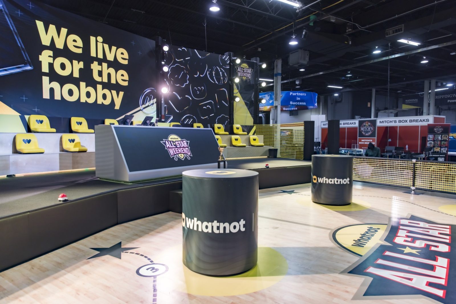 Whatnot All-Star Weekend display with yellow stadium seating, “We live for the hobby” signage, and a box-breaks booth.
