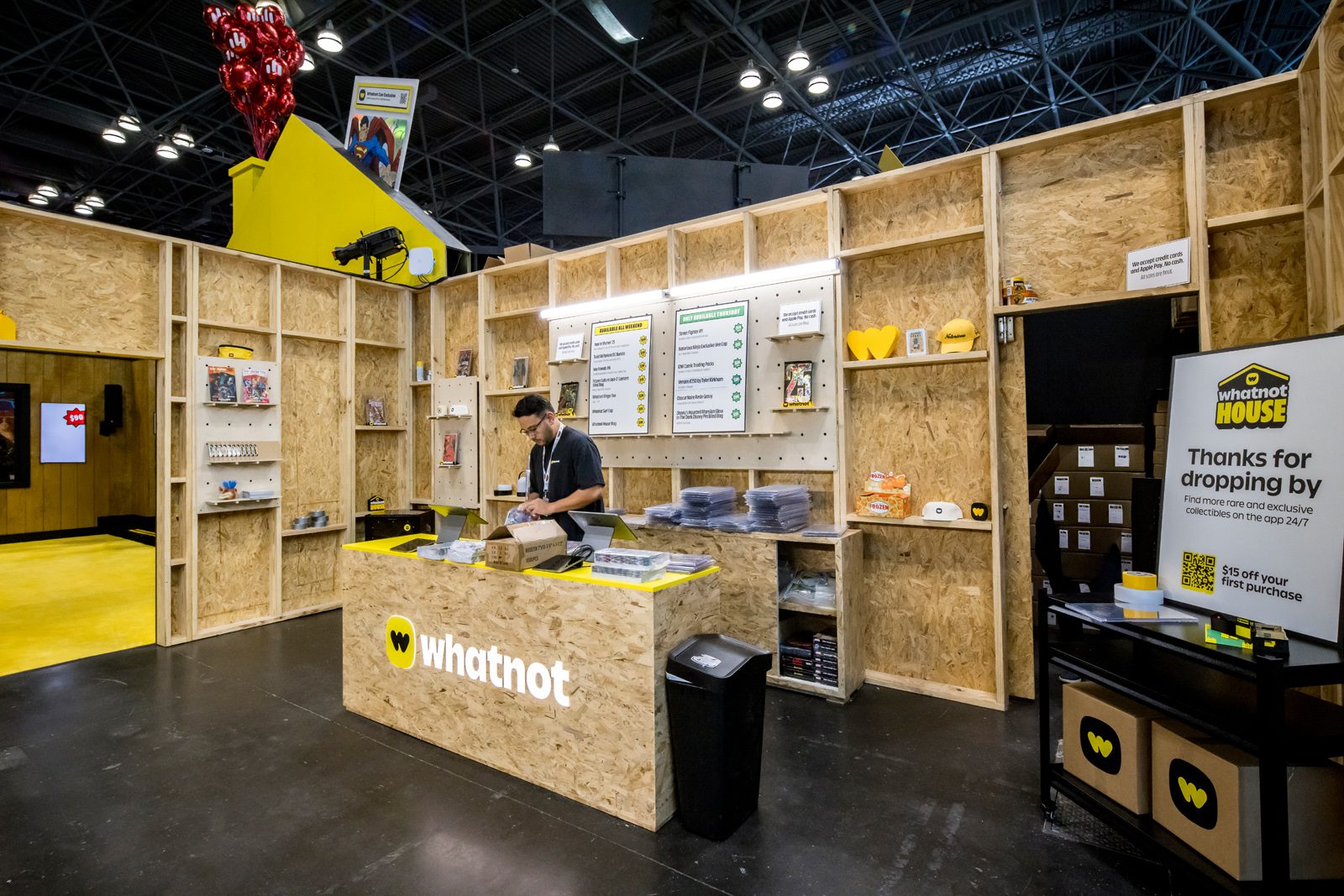 Whatnot House trade show booth with a staff member at the counter, collectibles on shelves, and a sign offering $15 off a first purchase
