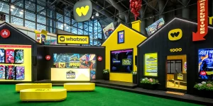 Whatnot House exhibit booth with yellow-and-black branding, comic displays, shop signage, and seating inside a convention hall.