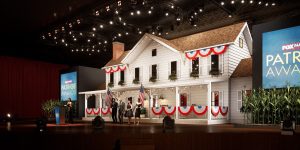 Stage set with a white house facade, American bunting, people, and screens displaying Fox Nation Patriot Awards