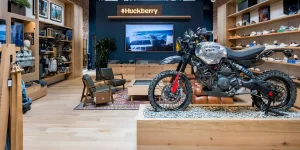 Huckberry store interior featuring a motorcycle display, clothing and footwear shelves, and the Huckberry logo
