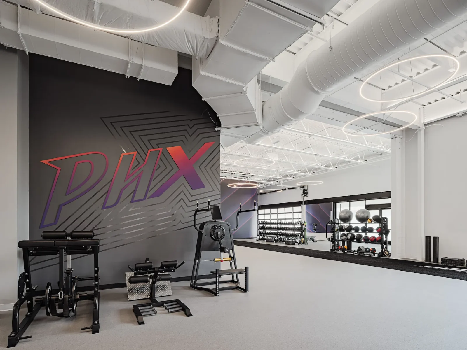 Basketball training gym with exercise equipment, medicine balls, and a large PHX wall logo