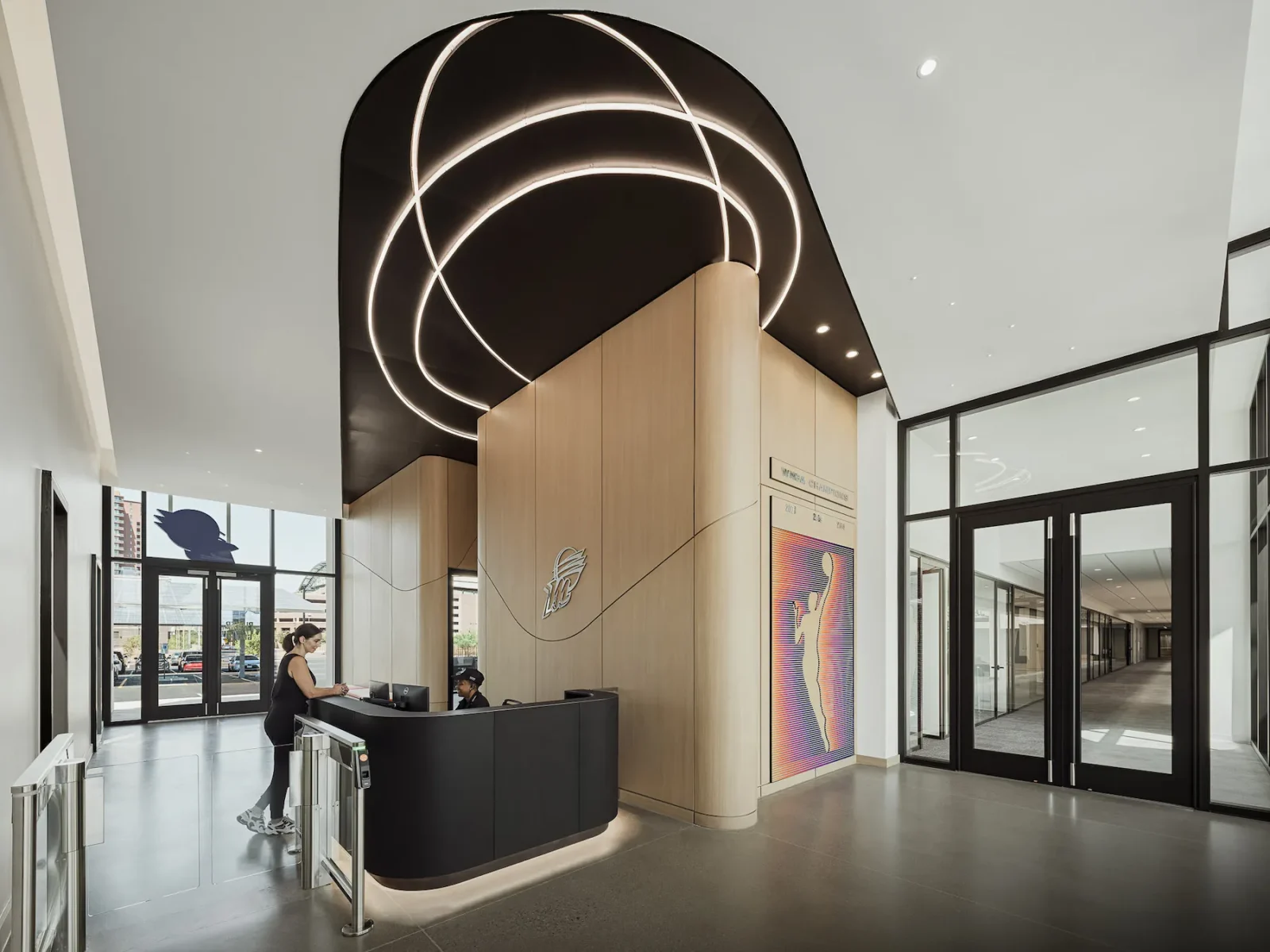 Reception lobby featuring the Phoenix Mercury logo, curved front desk, wood paneling, and illuminated circular ceiling lights.