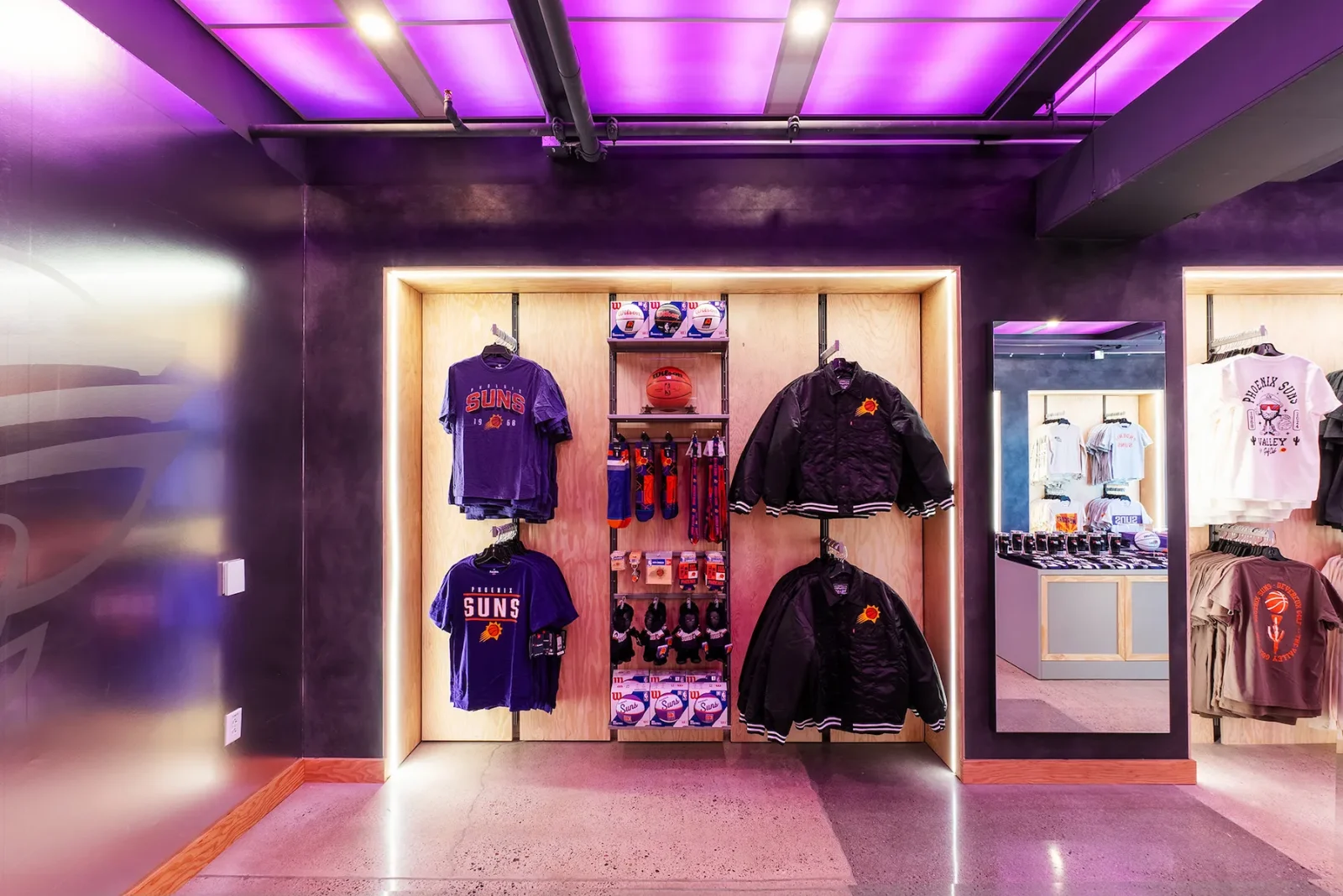 Phoenix Suns team store display featuring Suns shirts, jackets, basketballs, and other merchandise.