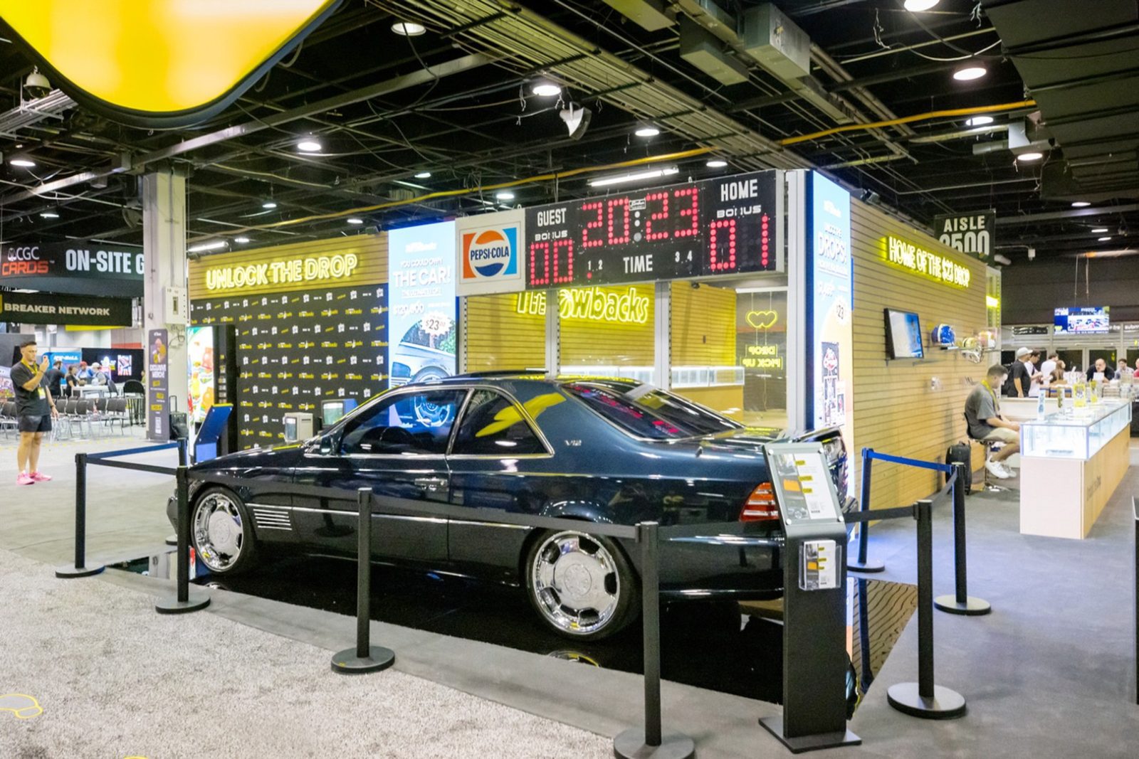 Black classic coupe displayed behind stanchions at a convention exhibit