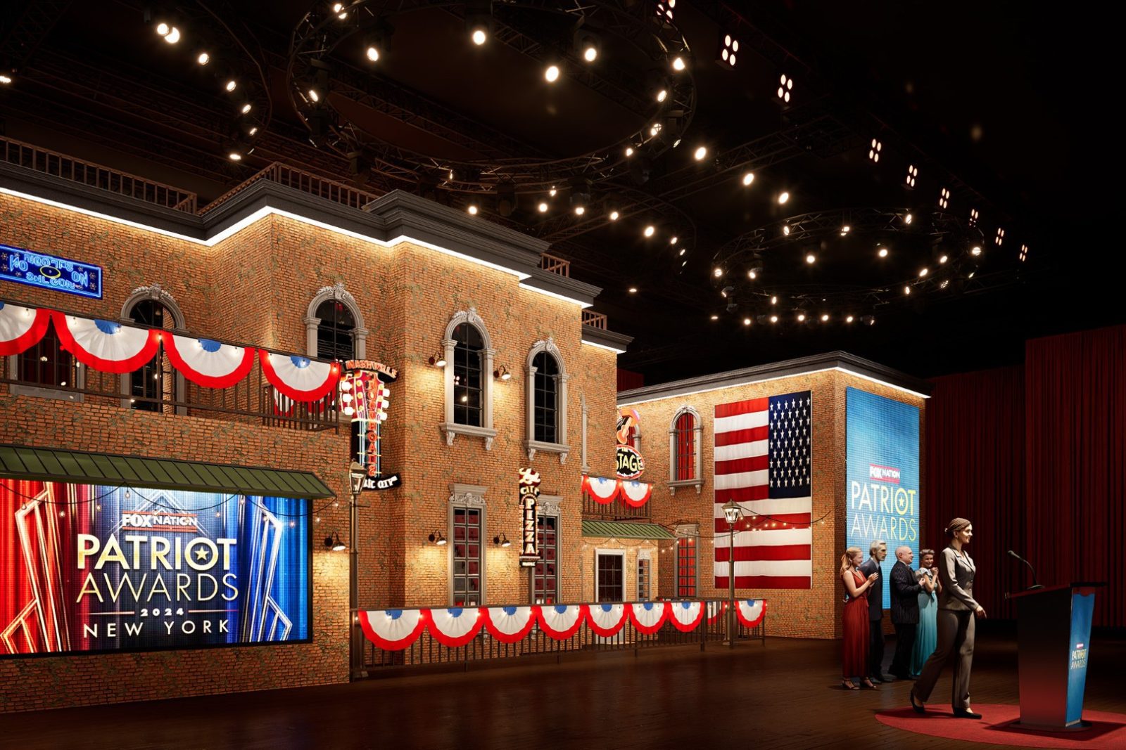 Stage set for the Fox Nation Patriot Awards 2024 in New York, with brick facades, American flags, patriotic bunting, and people onstage.