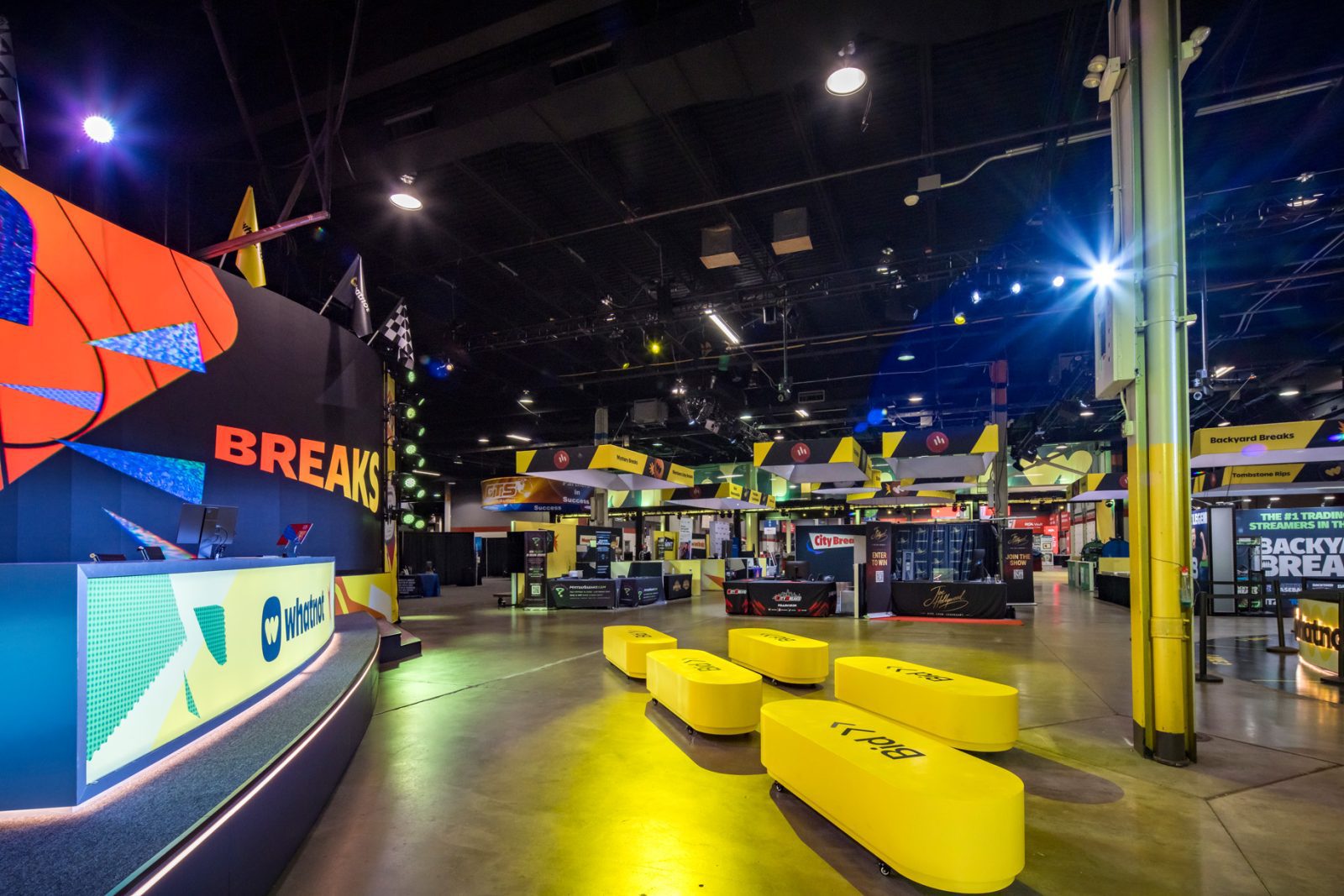 Whatnot-branded event floor with a Breakers stage, trading card booths, and yellow seating benches.