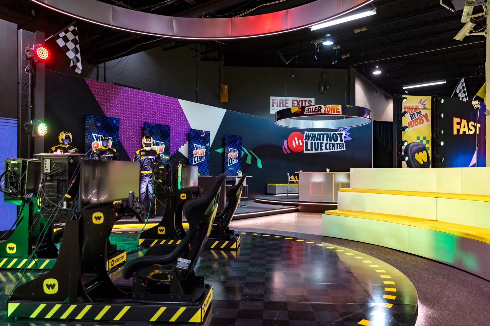 Whatnot Live Center booth with racing simulators, gaming screens, stage seating, and checkered-flag decor