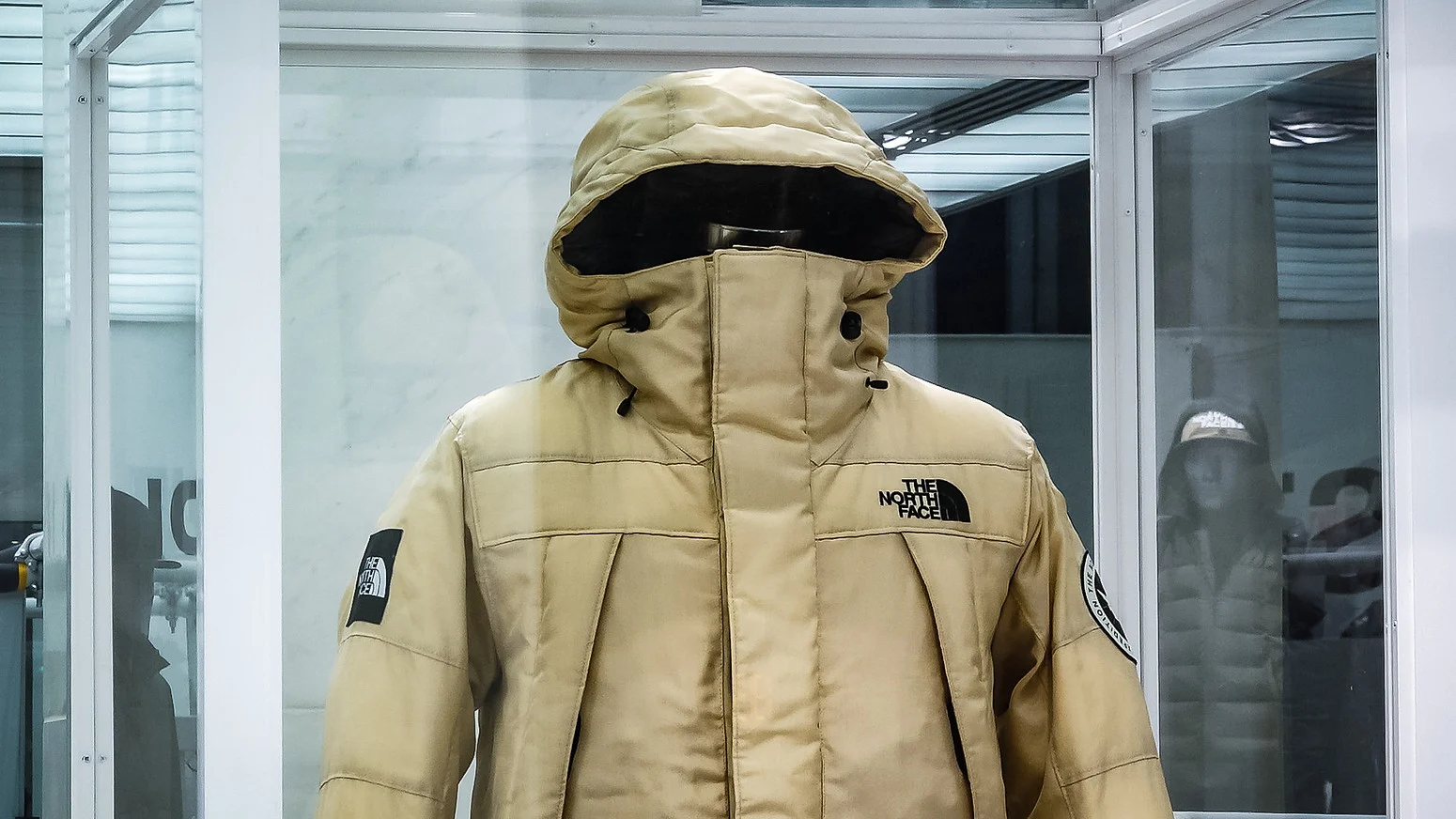 Beige The North Face hooded winter jacket displayed on a mannequin.