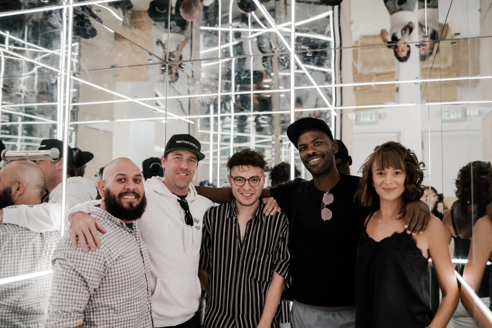 Five people pose together in a mirrored room.