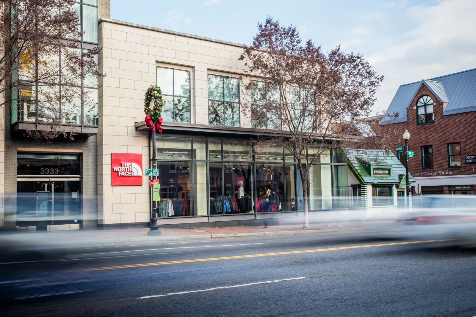 The North Face storefront with clothing displayed in the windows and a holiday wreath outside