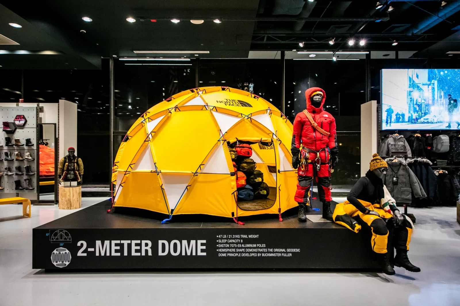 The North Face store display featuring a yellow 2-METER DOME tent, mountaineering mannequins, and outdoor gear.