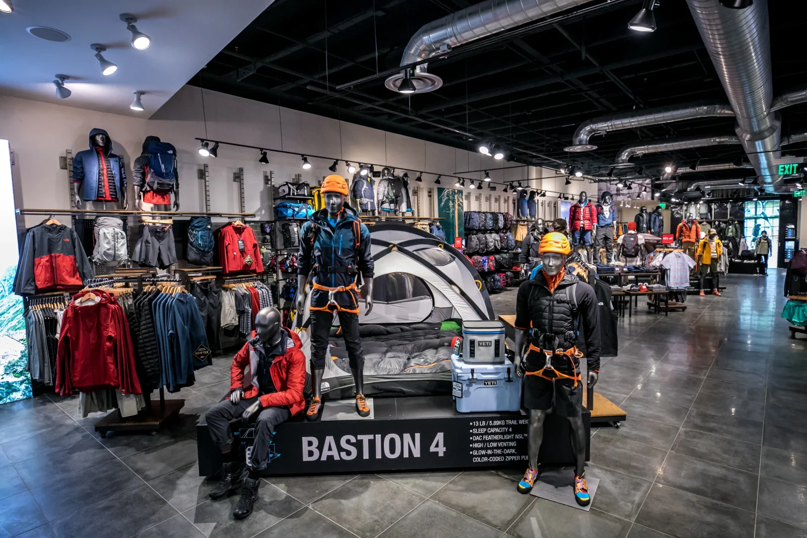 Outdoor apparel store interior with mannequins, camping gear, and a Bastion 4 tent display.