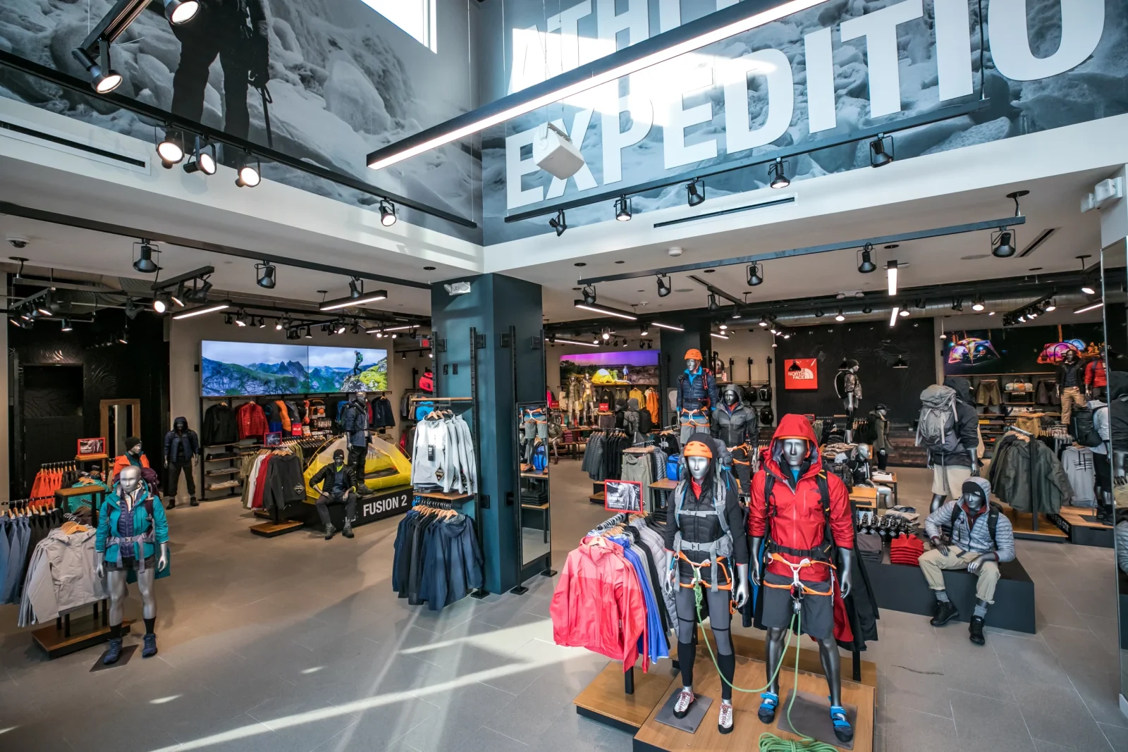 The North Face outdoor apparel store interior with mannequins in expedition gear, clothing racks, and large “EXPEDITION” lettering