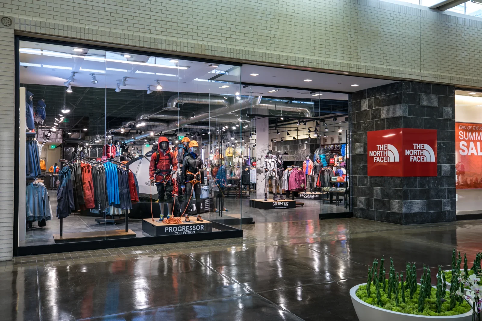 The North Face outdoor clothing store display with mannequins, jackets, gear, and storefront signage in a shopping mall.