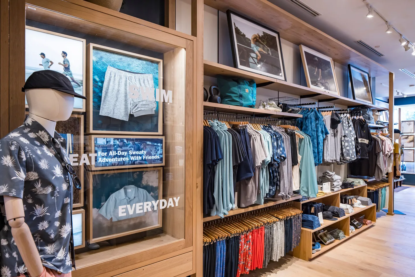 Huckberry retail display with a mannequin in a floral shirt, swimwear signage, framed outdoor photos, and racks of clothing.