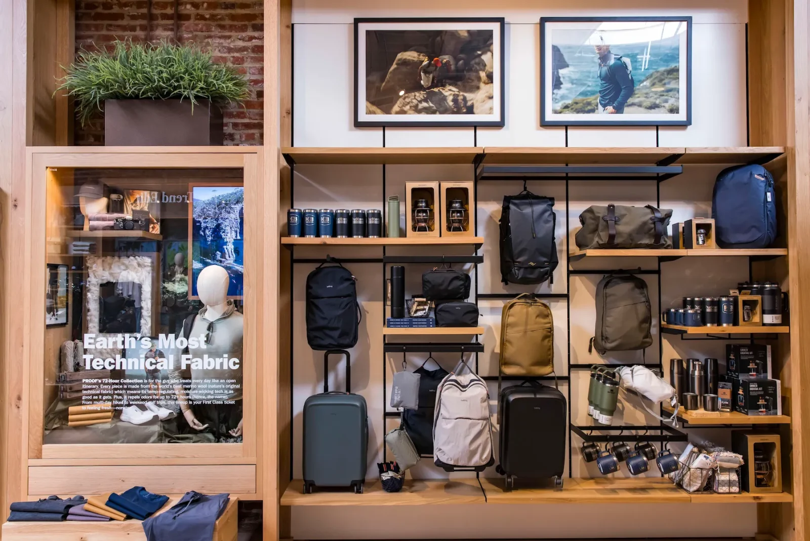 Huckberry store display with backpacks, luggage, drinkware, clothing, framed outdoor photos, and a sign reading “Earth’s Most Technical Fabric.”