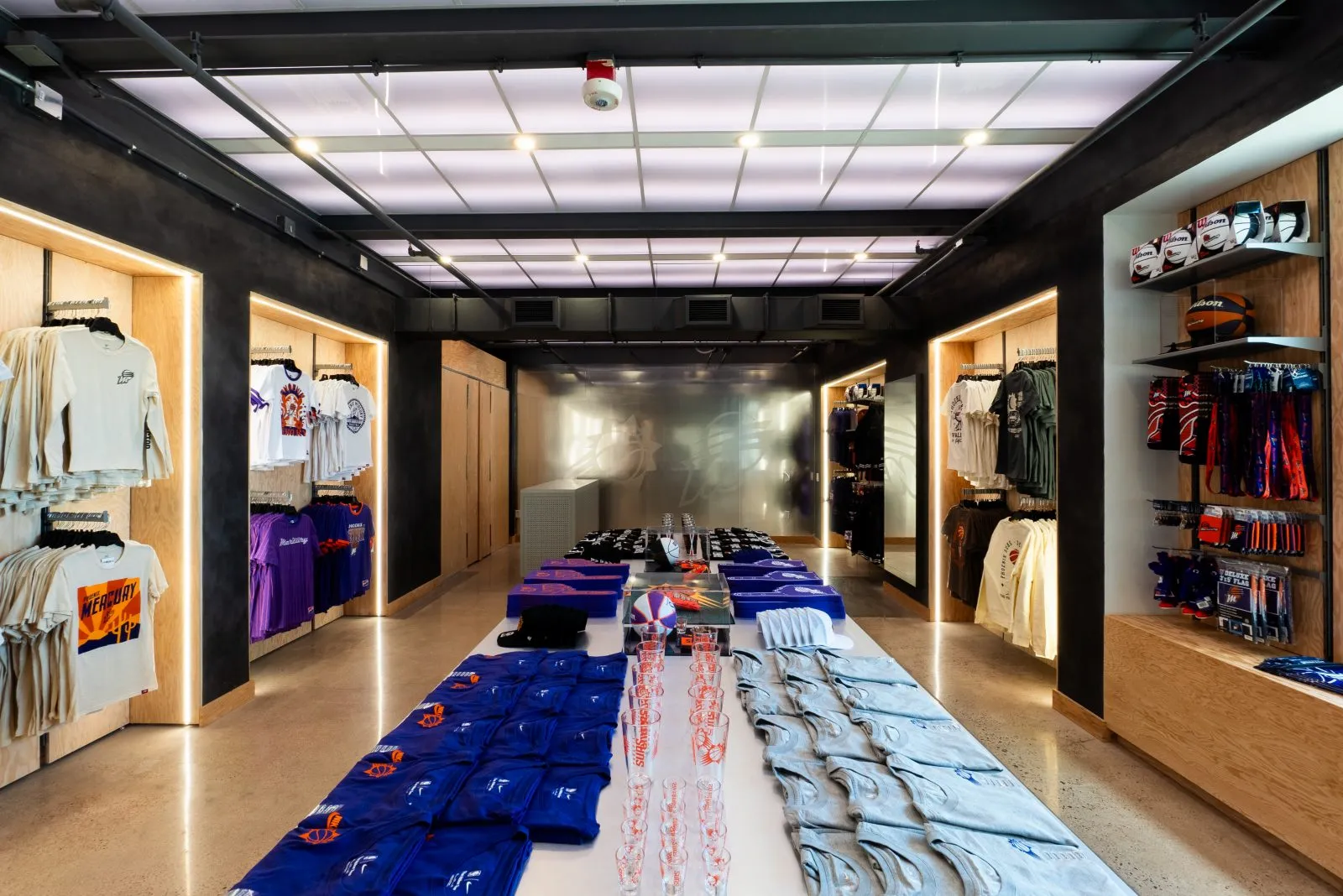 Interior of a Phoenix Suns team store displaying apparel, basketballs, shorts, shirts, and drinkware.