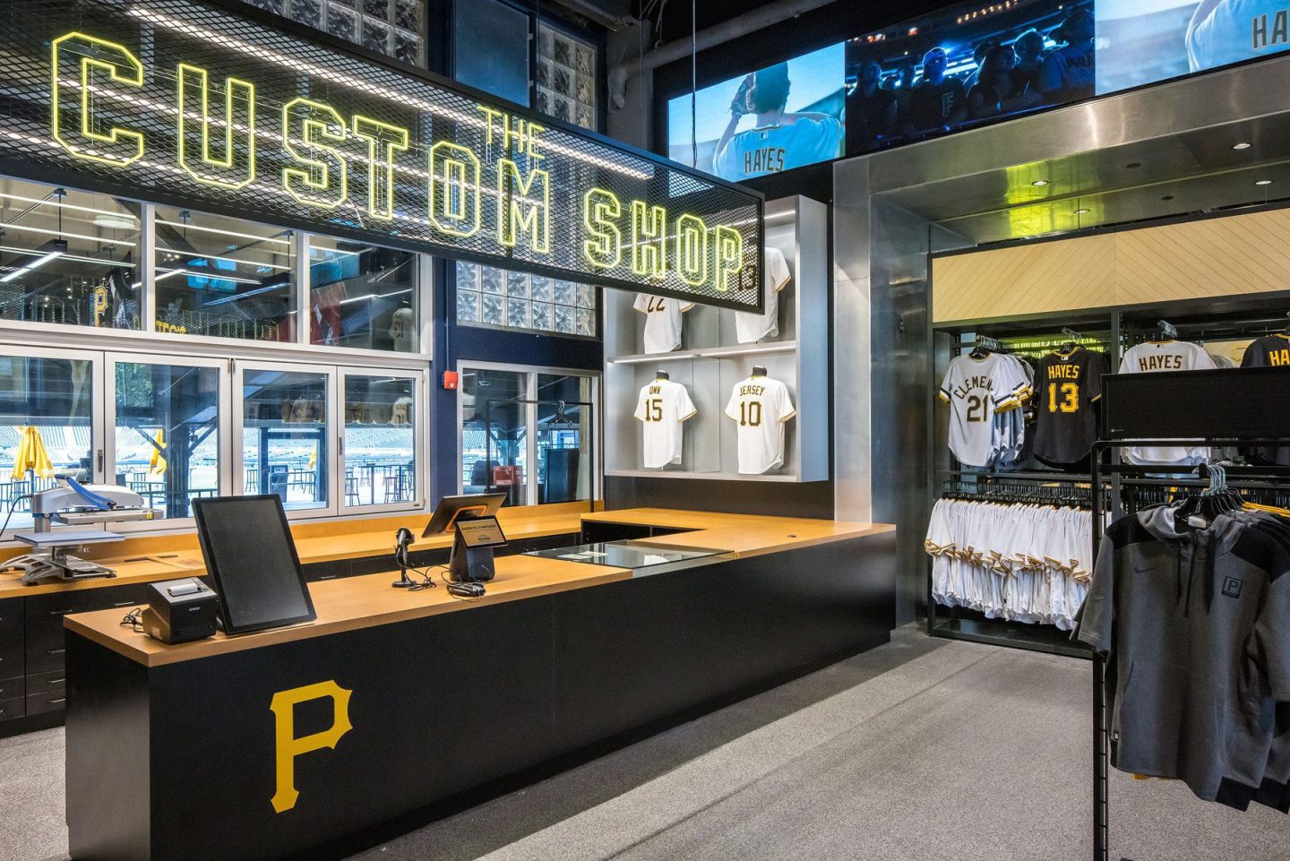 Interior of a Pittsburgh Pirates custom shop with a prominent "CUSTOM SHOP" sign, jersey displays, and merchandise racks.
