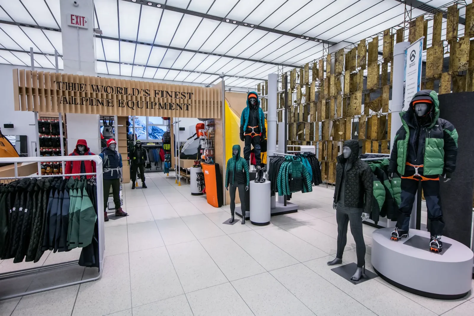 Interior of a The North Face outdoor apparel store with mannequins in technical clothing, jackets on racks, and the sign “The world's finest alpine equipment.”