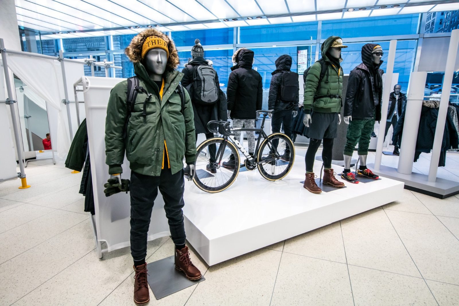 Mannequins model winter outdoor clothing beside bicycles in a retail display