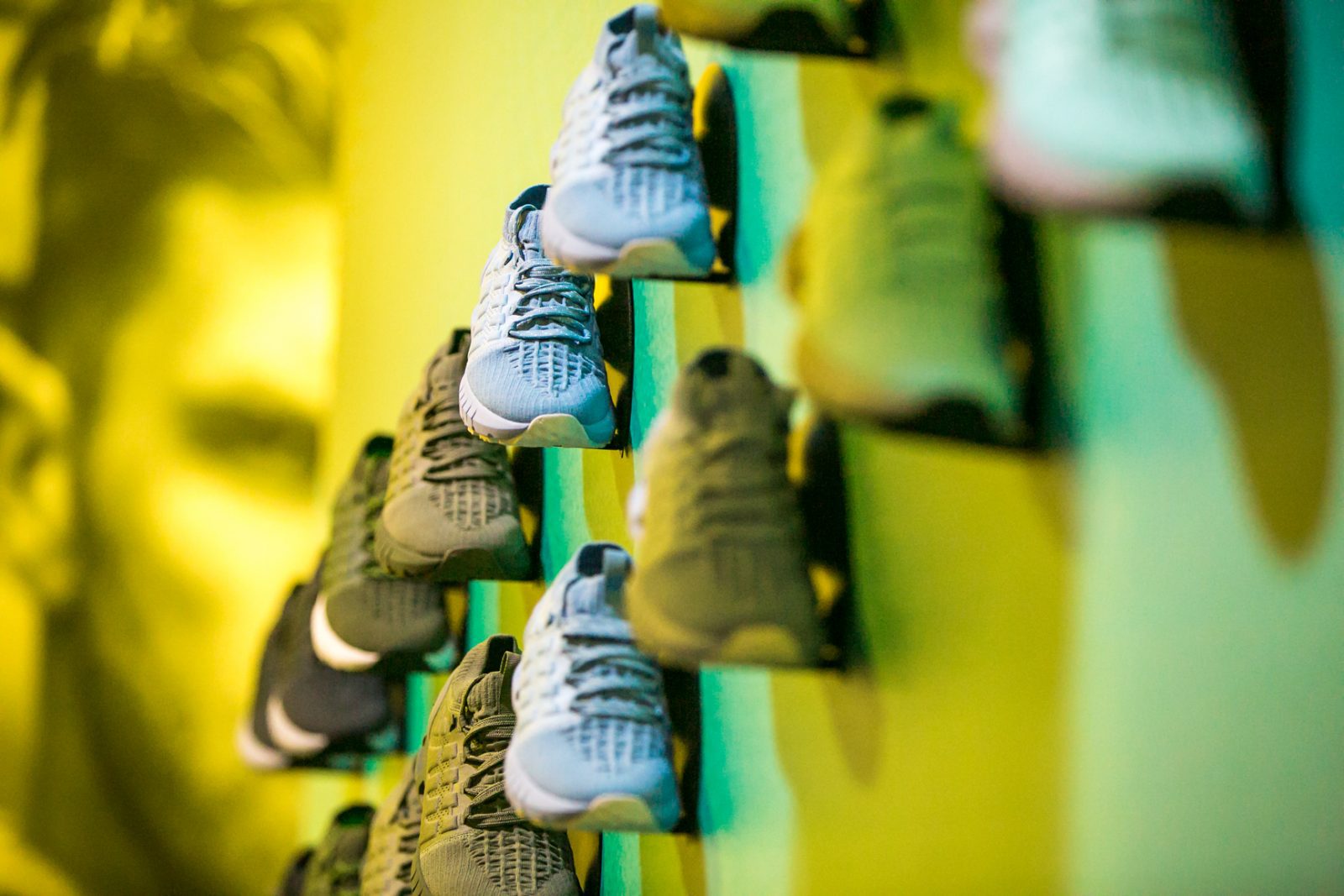 Rows of athletic shoes displayed on wall-mounted shelves in a brightly lit retail space