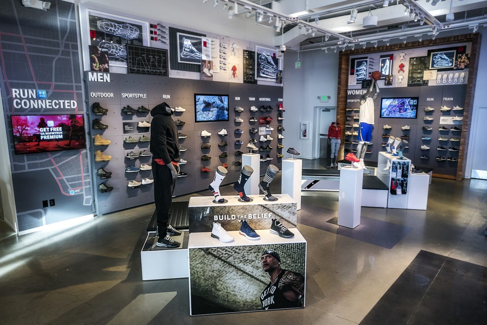 Athletic footwear store interior with men's and women's shoe displays, mannequins, and promotional signage.