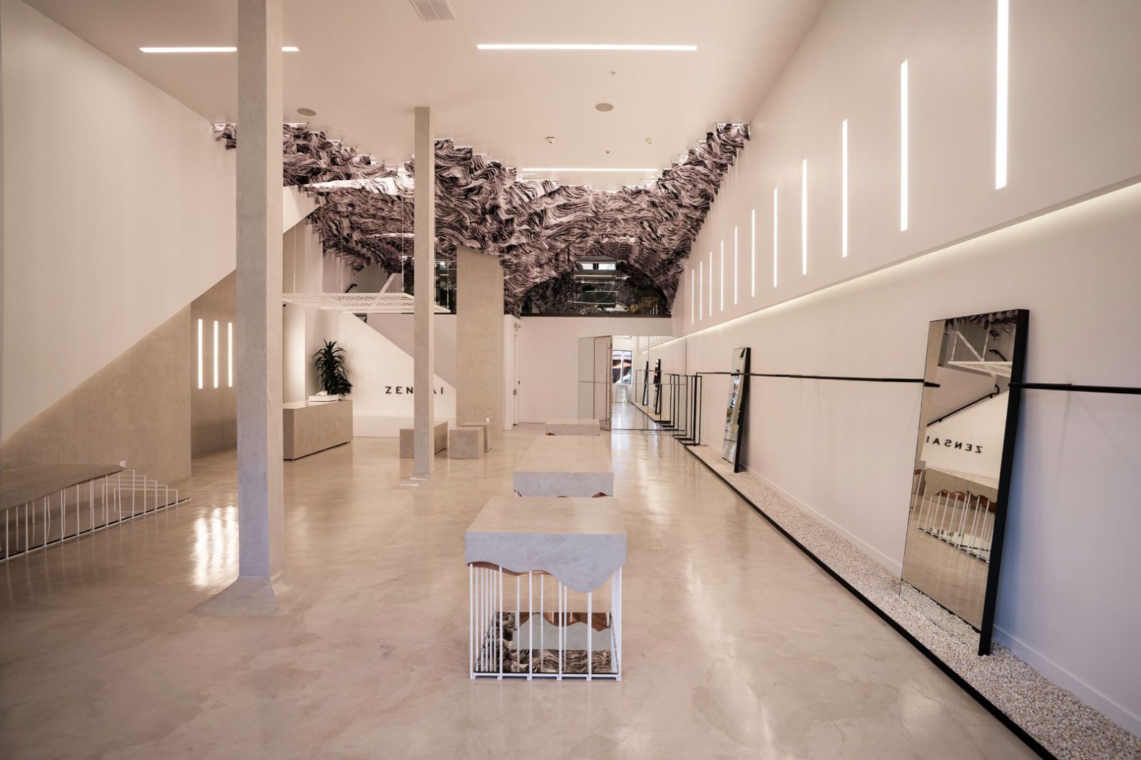 Interior of Zensai featuring a minimalist gallery-like space, sculptural black-and-white ceiling installation, mirrors, benches, and illuminated walls.