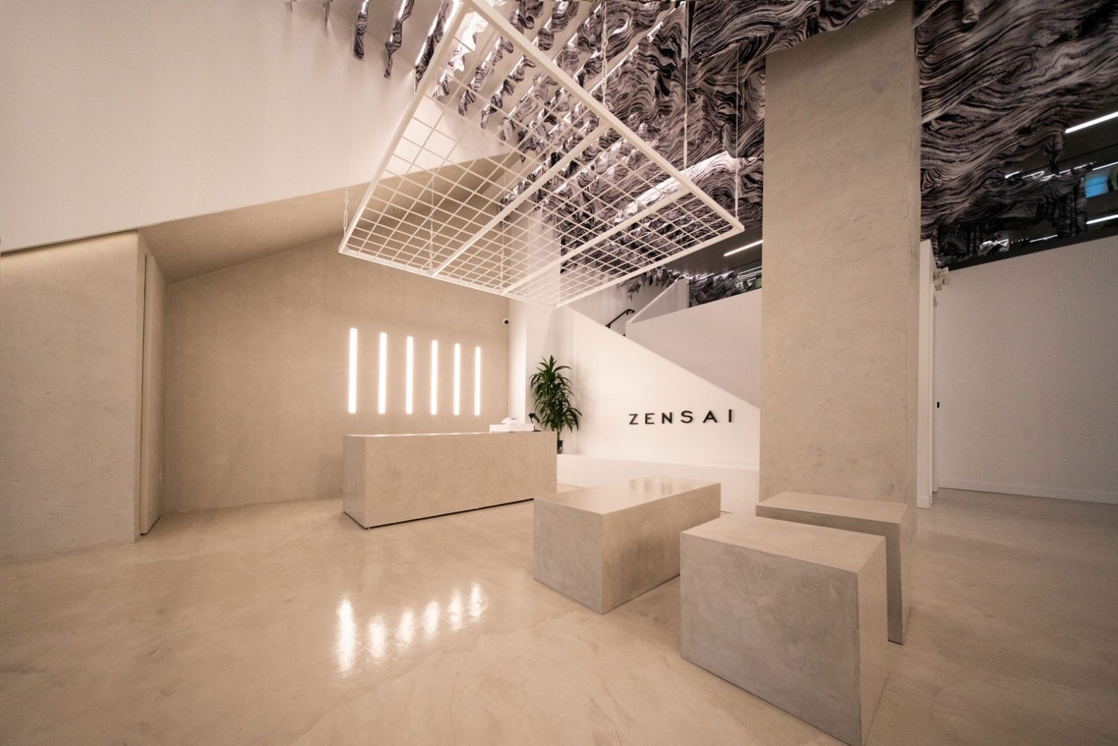 Minimalist Zensai interior with a reception desk, sculptural seating, mirrored marbled ceiling, and ZENSAI wall lettering