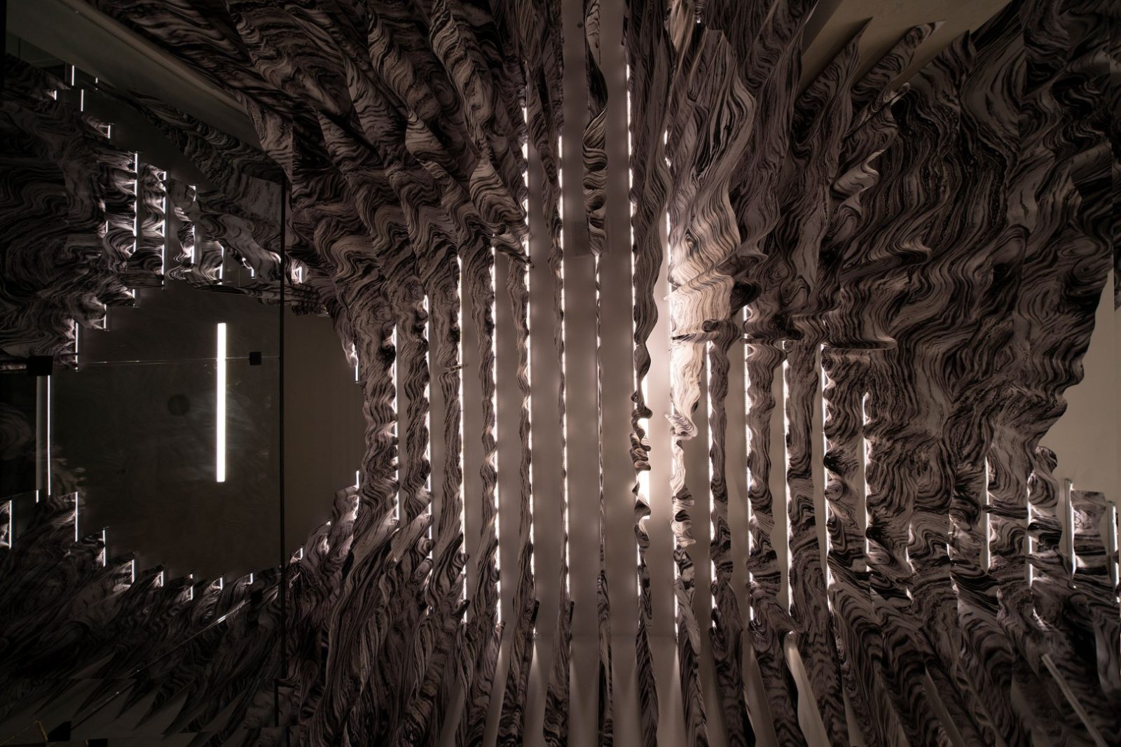 Dark interior lined with swirling black-and-white marble surfaces and narrow vertical illuminated light slits