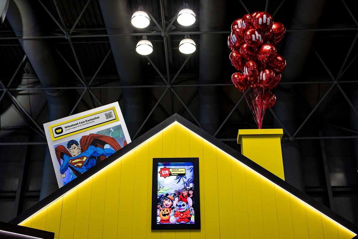 Whatnot convention booth with red branded balloons, a Superman display, and a colorful promotional screen