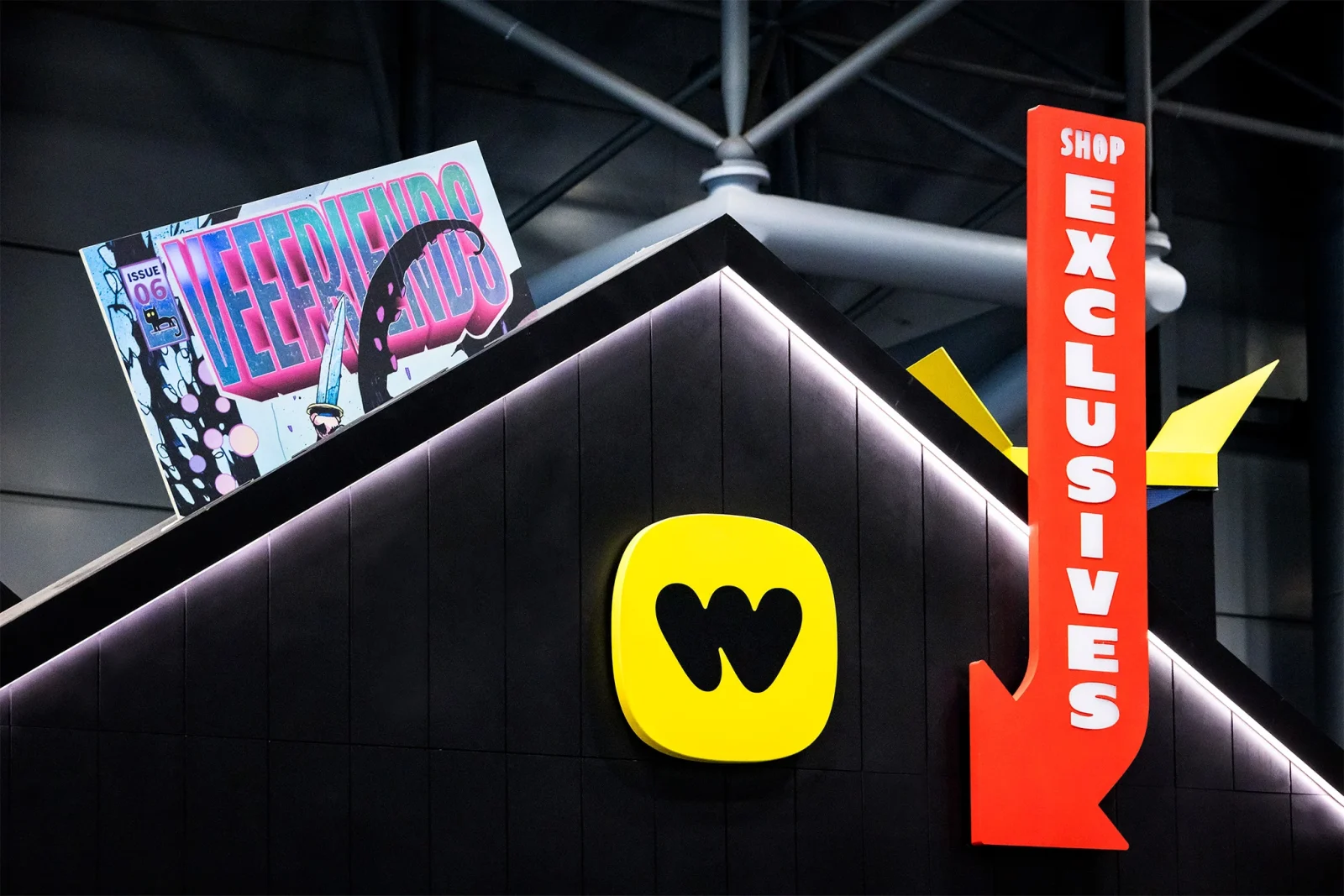 Music shop storefront sign with a red SHOP MUSIC arrow, yellow logo, and colorful magazine poster